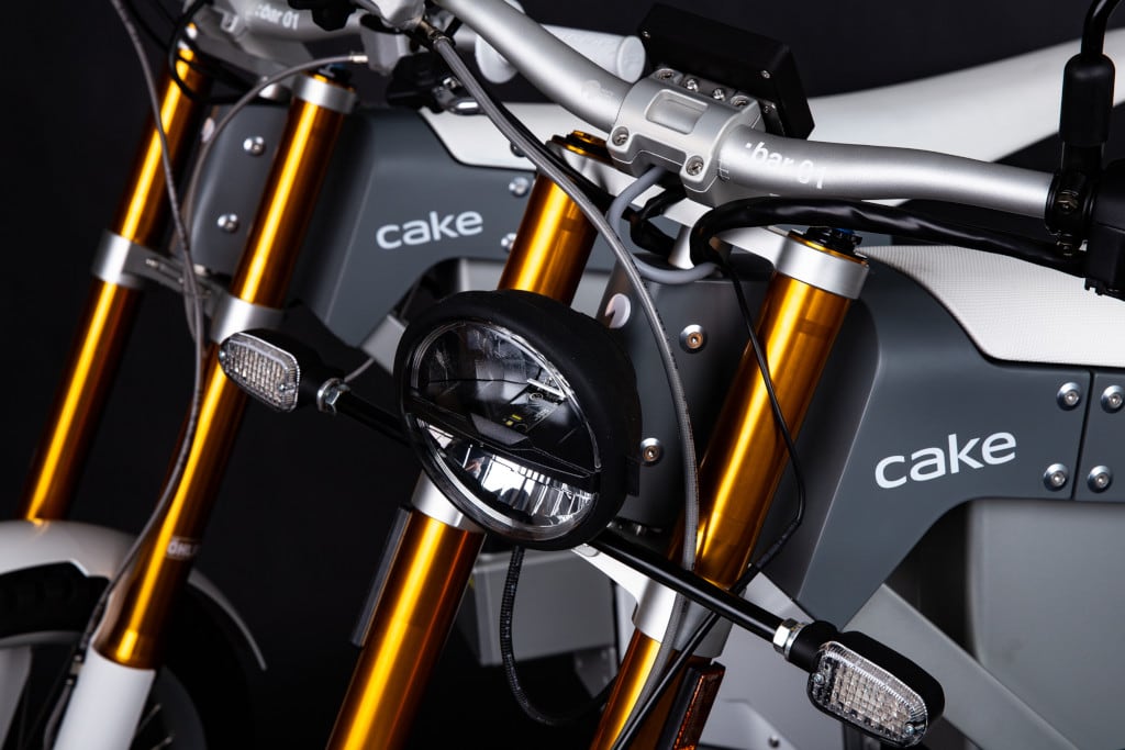 Cake-Kalk E-Motorrad  zwei Bikes vor Schwarz Lichtdetail