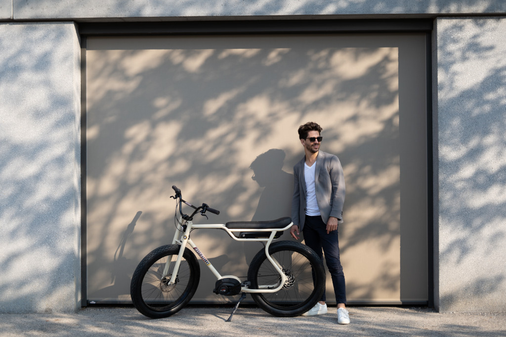 Biggie-Ruff-Cycles-e-Bike-Pedelec- mit Mann vor einem weißen Tor